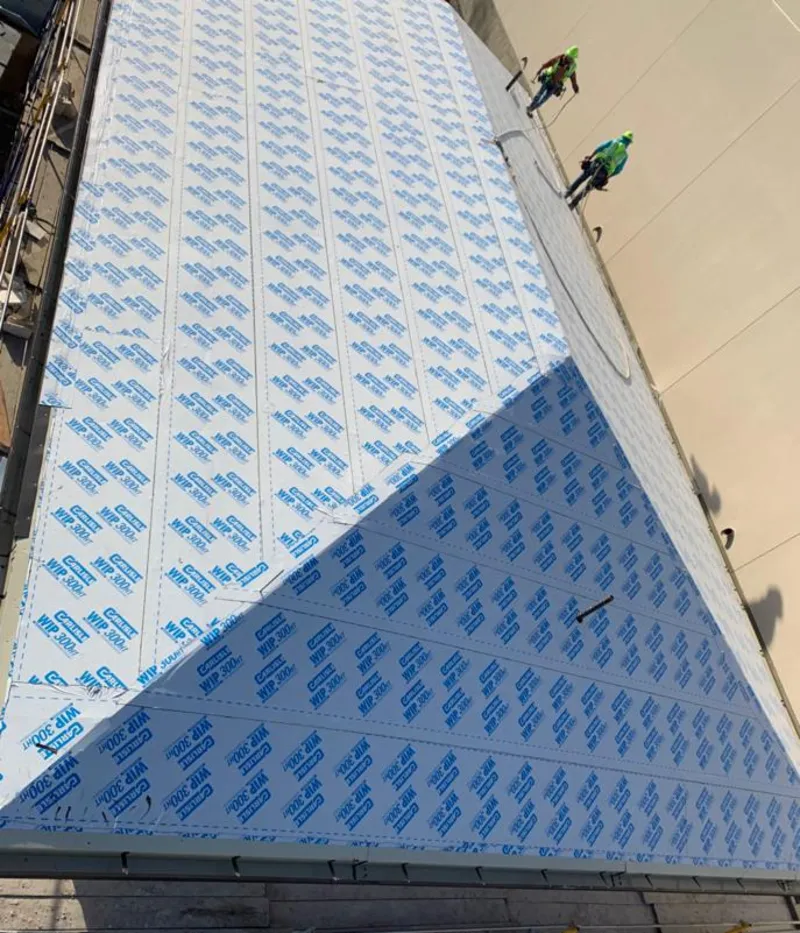 Professional roofers installing underlayment on a metal roof in Tichigan